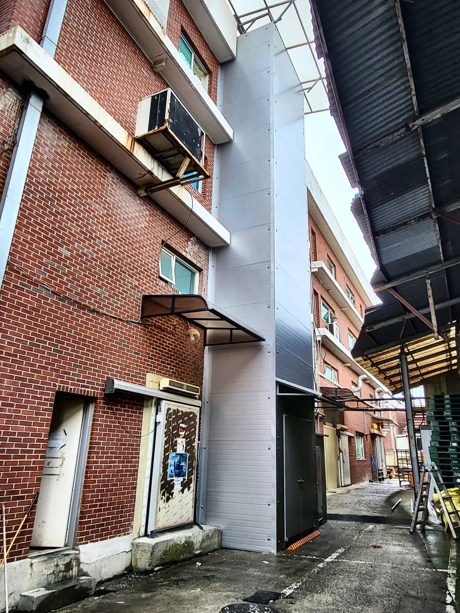 벽돌 건물 외벽에 판넬로 마감해 설치한 고층 화물용 리프트